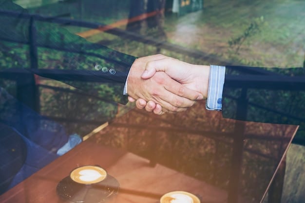 A close-up shot of two hands shaking over a table, symbolizing a successful wage negotiation. The background is blurred to focus on the hands in agreement.