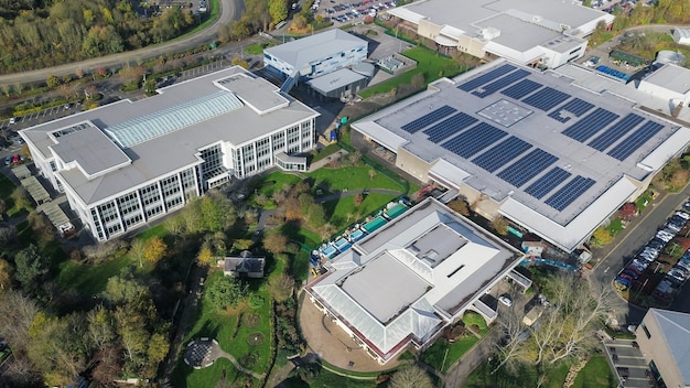 Solar panels on the roof of a factory, illustrating renewable energy usage and reduced carbon emissions. The factory is surrounded by green fields, indicating a commitment to sustainability in a natural environment.