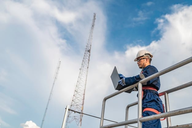 A close-up shot of a technician working on the top of a 5G cell tower in a rural setting. The technician is wearing safety gear and is focused on installing or maintaining the equipment. In the background, there are rolling hills and farmland.