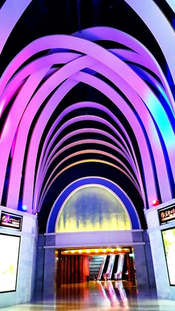 A Broadway stage featuring a complex set design with LED screens displaying dynamic backgrounds and projections. Actors are interacting with the digital environment, and the scene evokes a futuristic or fantasy world.